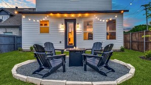 A house with a deck, two Adirondack chairs, and a fire pit.