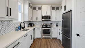 A modern kitchen with white cabinets, stainless steel appliances, and a tiled backsplash.