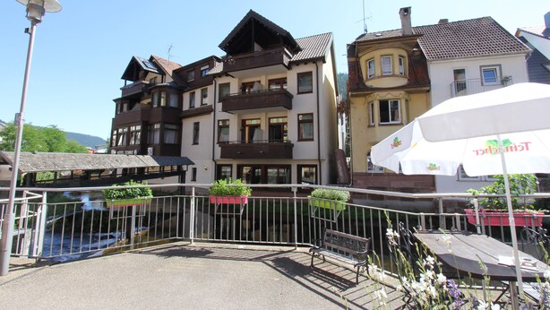Un hôtel doté de nombreux balcons, d’un espace extérieur aménagé et offrant une vue sur une rivière.