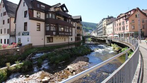 Un hôtel avec une enseigne indiquant qu’il s’agit également d’un restaurant, situé au bord d’une rivière, avec un pont en arrière-plan.