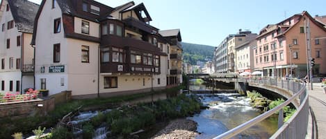 Un hotel con un letrero que indica que es restaurante, ubicado junto a un río con un puente al fondo.