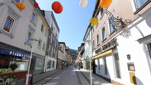 Une rue bordée d’immeubles, dont une pizzeria et un magasin dont l’enseigne indique « SONN ».