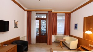 Une chambre d’hôtel équipée d’un lit, d’un bureau, d’une chaise, d’un canapé, d’une télévision et d’une fenêtre avec des rideaux.