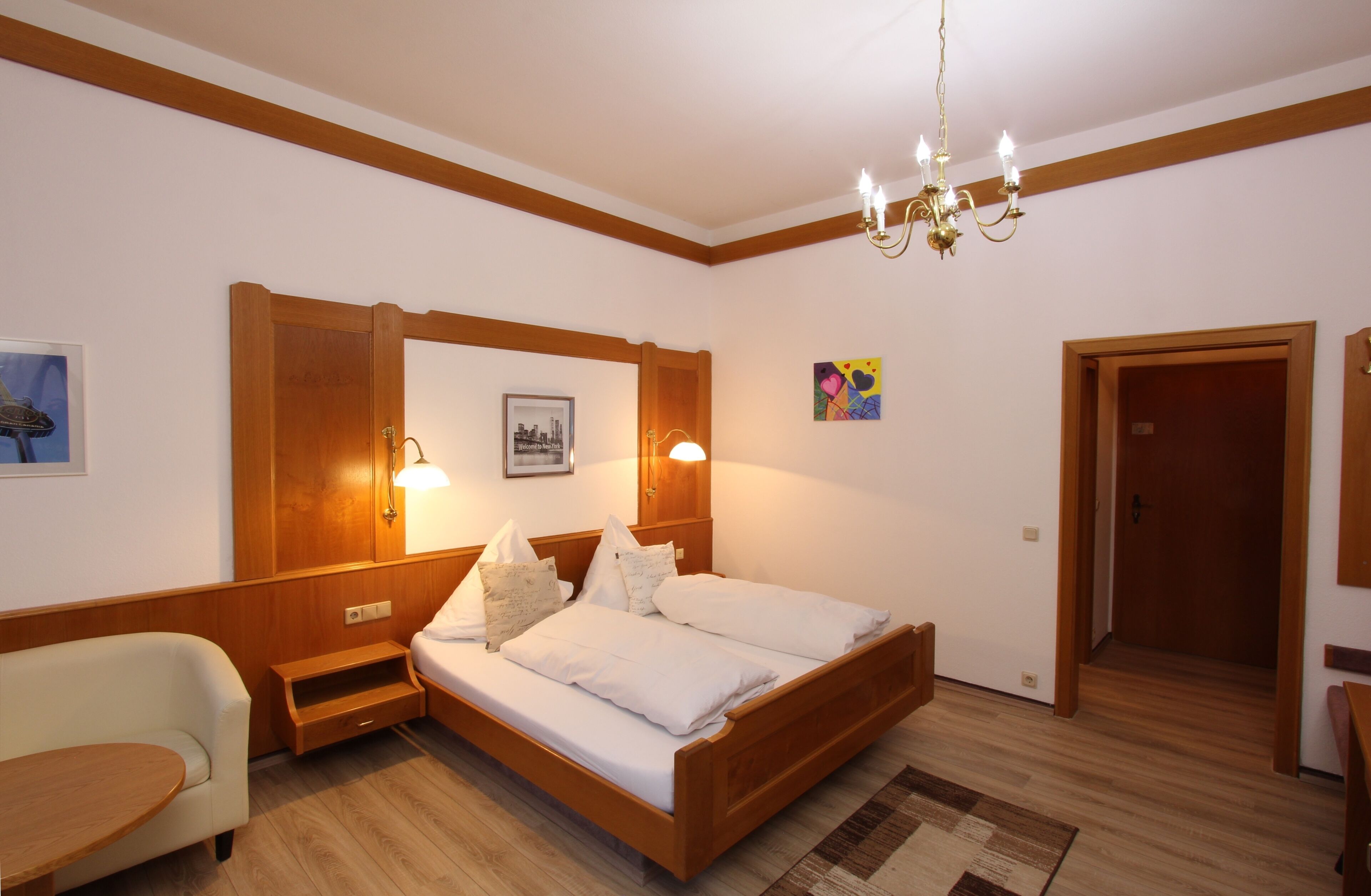 Un dormitorio con una cama de madera, una mesita de noche, una silla y un escritorio.