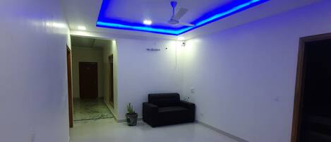 A spacious room with a flat floor, a ceiling fan, and a potted plant.