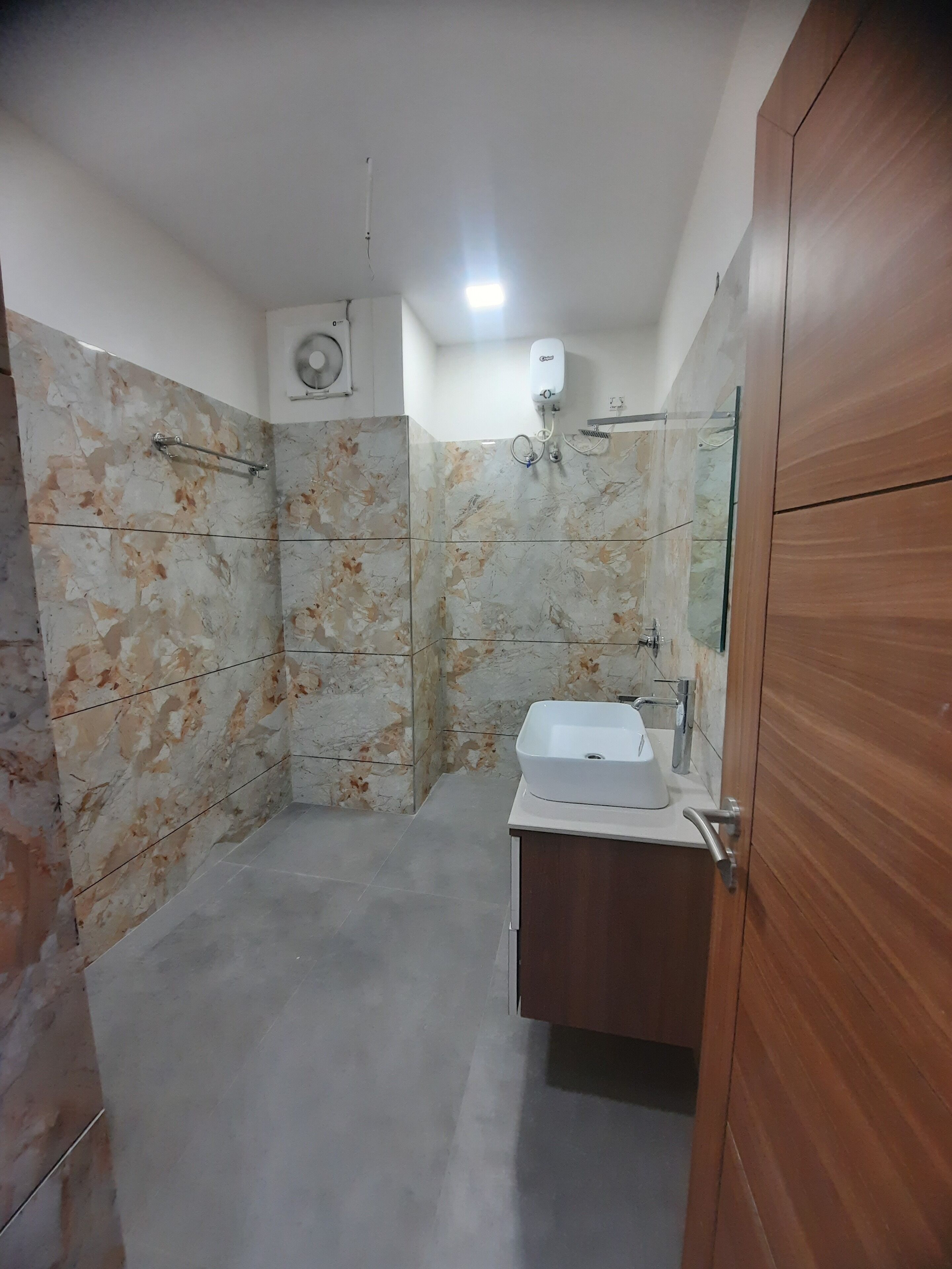 Une salle de bain avec un mur en marbre, un lavabo blanc et un meuble en bois.