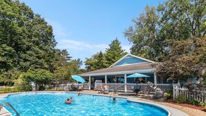 A swimming pool with a covered patio area and a building with a blue roof. - Sandy Feet Retreat: Like-New, Harbor Club South Haven, Year-Round Pool & Hot Tub (South Haven)