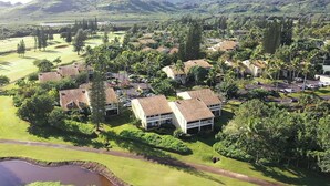 A residential area with houses, a golf course, and a pond.