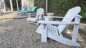Een terras met Adirondack-stoelen, een kleine tafel en een stenen pilaar.
