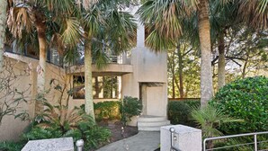 A pathway leading to a building with a concrete structure, surrounded by palm trees and greenery. - The Iconic Round House (St Simons Island)