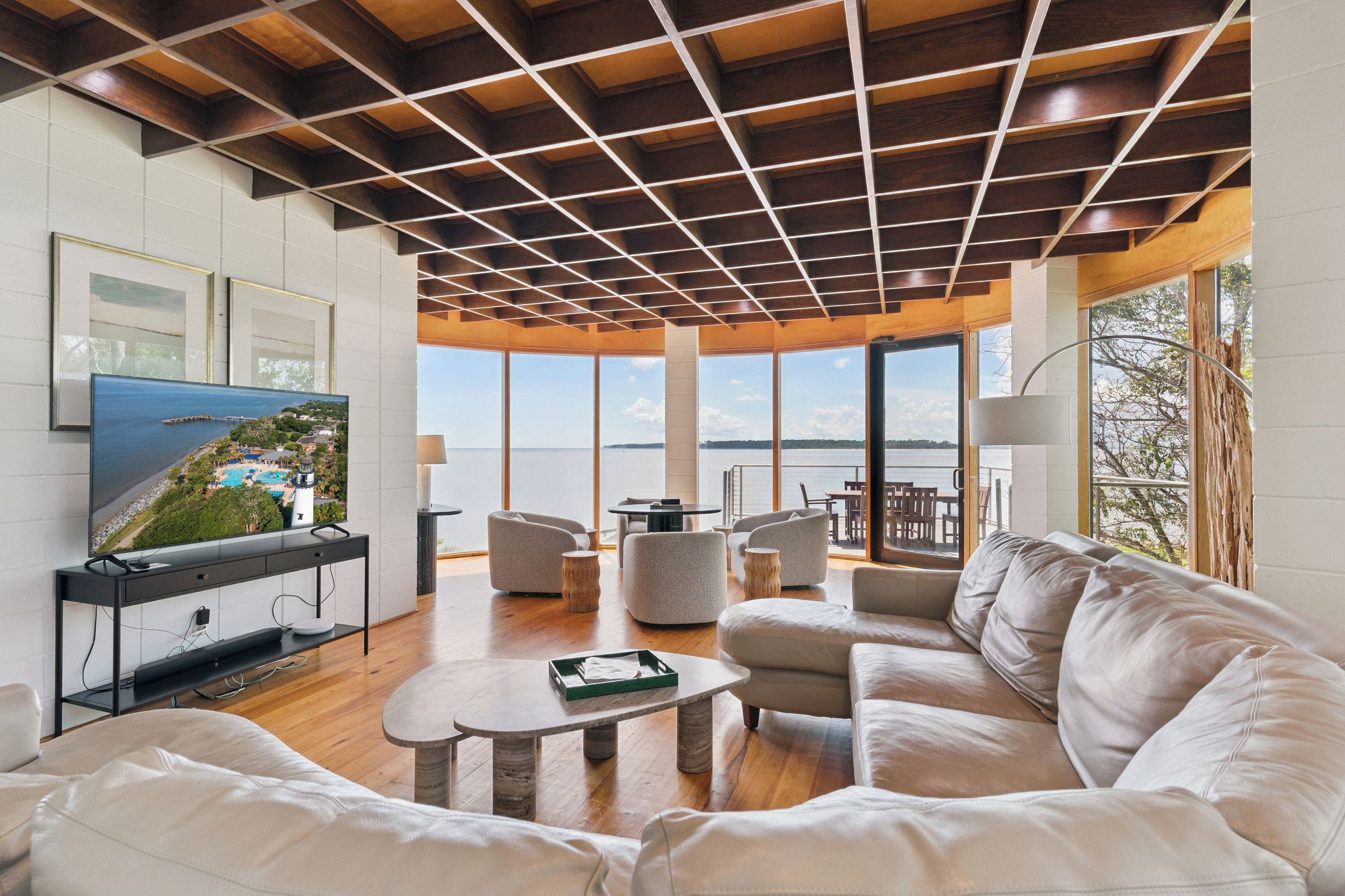 A modern living room with a large flat-screen TV, comfortable seating, and a view of the outdoors.