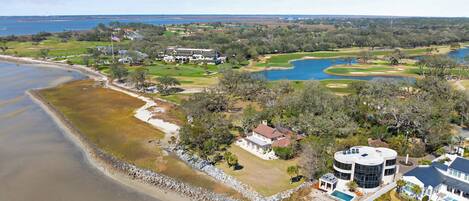 A coastal property with a golf course, a large house, and a swimming pool.