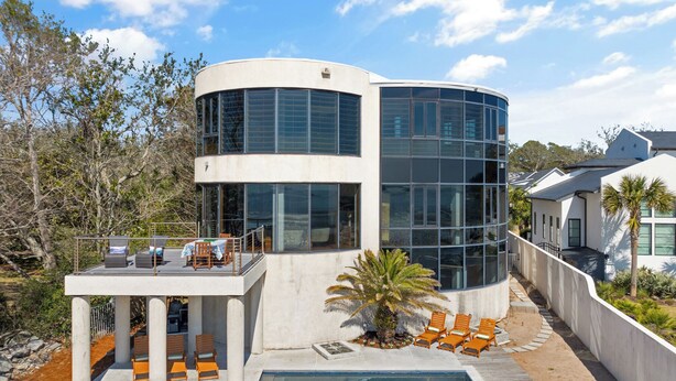 A modern house with a pool, outdoor seating, and a large glass facade. - The Iconic Round House (St Simons Island)