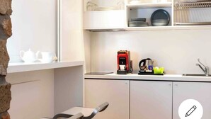 A compact kitchen with white cabinets, a coffee machine, and a sink.