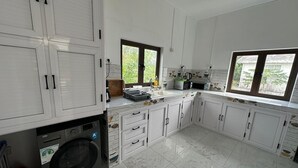 A modern kitchen with white cabinets, a built-in washing machine, and a large window providing natural light. - 3-bedroom villa in delightful Calodyne Saint Francois with AC, WiFi (CALODYNE SAINT FRANCOIS)