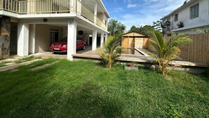 A two-story house with a covered porch, a red car parked in the driveway, and a small wooden shed in the yard. - 3-bedroom villa in delightful Calodyne Saint Francois with AC, WiFi (CALODYNE SAINT FRANCOIS)