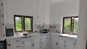 A modern kitchen with white cabinets, a microwave, and a sink. There are two windows providing natural light and a view of greenery outside. - 3-bedroom villa in delightful Calodyne Saint Francois with AC, WiFi (CALODYNE SAINT FRANCOIS)