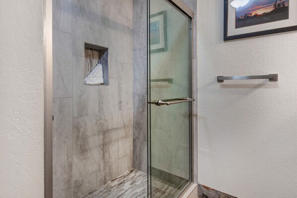 A glass-enclosed shower with a metal handle and a towel rack on the wall.