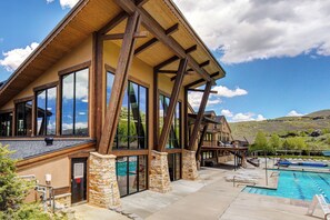 A large building with a pool, stone pillars, and large windows.