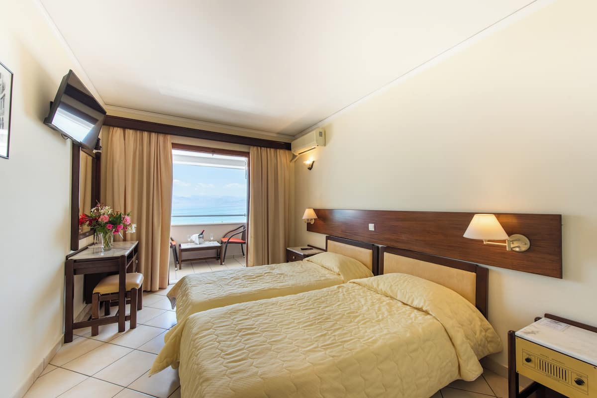 A hotel room with two beds, a desk with a chair, a TV, and a window with curtains.