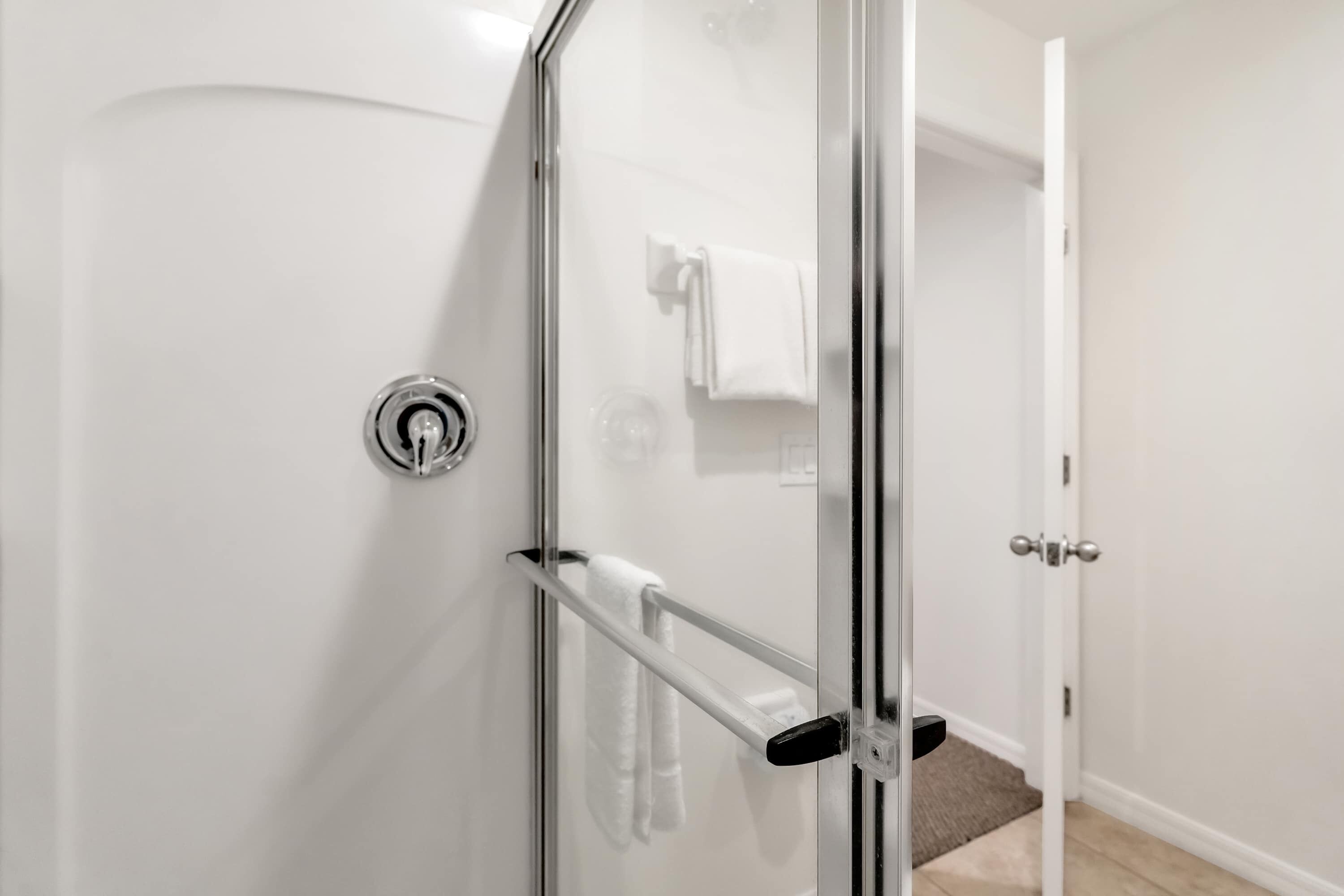 Une cabine de douche en verre avec un porte-serviettes et une porte dotée d’une poignée.
