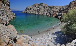 Eine felsige Küste mit klarem türkisblauem Wasser und einem Sandstrand.