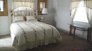 A bedroom with a bed, bedside table, lamp, and a chair.