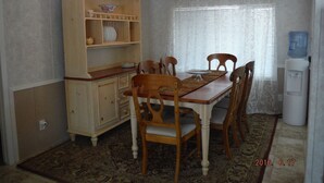 A dining room with a wooden table, four chairs, a cabinet with dishes, and a water dispenser.