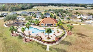 A residential area with a swimming pool, palm trees, and houses.