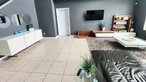 A modern living room with a white console, a flat-screen TV, a sofa, and a coffee table.