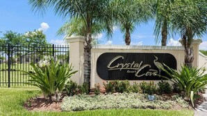 A sign for Crystal Cove Resort with a clear view of the entrance, surrounded by palm trees and a well-maintained lawn.