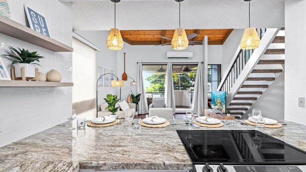 A modern kitchen with a granite countertop, a black stove, and pendant lighting.