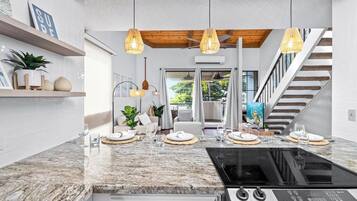 A modern kitchen with a granite countertop, a black stove, and pendant lighting.