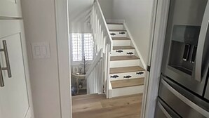 Una escalera conduce a un segundo piso, donde se encuentra un área de cocina a la derecha.