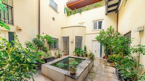 A courtyard with a central water feature, potted plants, and a tiled floor. - Exclusive Apartment with Jacuzzi in the Historic Center of Palermo (Palermo)