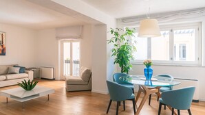 A modern living room with a glass dining table, blue chairs, a white sofa, and a large green plant. - Exclusive Apartment with Jacuzzi in the Historic Center of Palermo (Palermo)