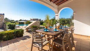 Eine Außenpatio mit Holztisch und -stühlen, einem Pool und Blick auf die umliegende Landschaft.