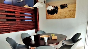 Un comedor con una mesa redonda, cuatro sillas y un cuadro de ganado en la pared.