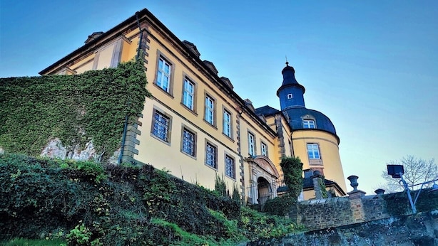 Un edificio histórico con una torre destacada y una amplia fachada con ventanas.