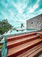 Um edifício de pedra com piscina e escadas de madeira que conduzem a ela.