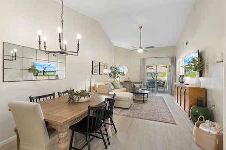 A dining area with a wooden table and chairs, a sofa, and a television.. PalmView LUX 2BR/2BA Retreat - Patio, Views, Pool & Spa, Private Gated Enclave