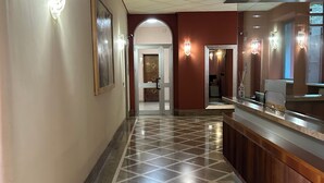 A hotel lobby with a check-in counter, a tiled floor, and wall-mounted light fixtures. - Comfort chic - Duomo in 5 minutes (Milano)