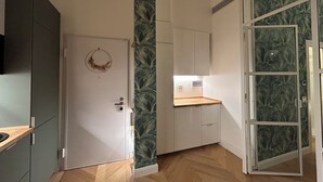 A modern kitchen with a wooden countertop, a white door with a wreath, and a view of the living area through a glass door. - Comfort chic - Duomo in 5 minutes (Milano)