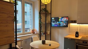 A modern kitchen with a round wooden table, a built-in oven, and a TV mounted on the wall displaying streaming services. - Comfort chic - Duomo in 5 minutes (Milano)