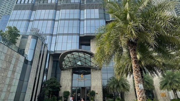 A tall, modern skyscraper with a glass facade, surrounded by palm trees and a well-maintained plaza. - Cozy- Vinhomes Central Park Apartments (Ho Chi Minh City)