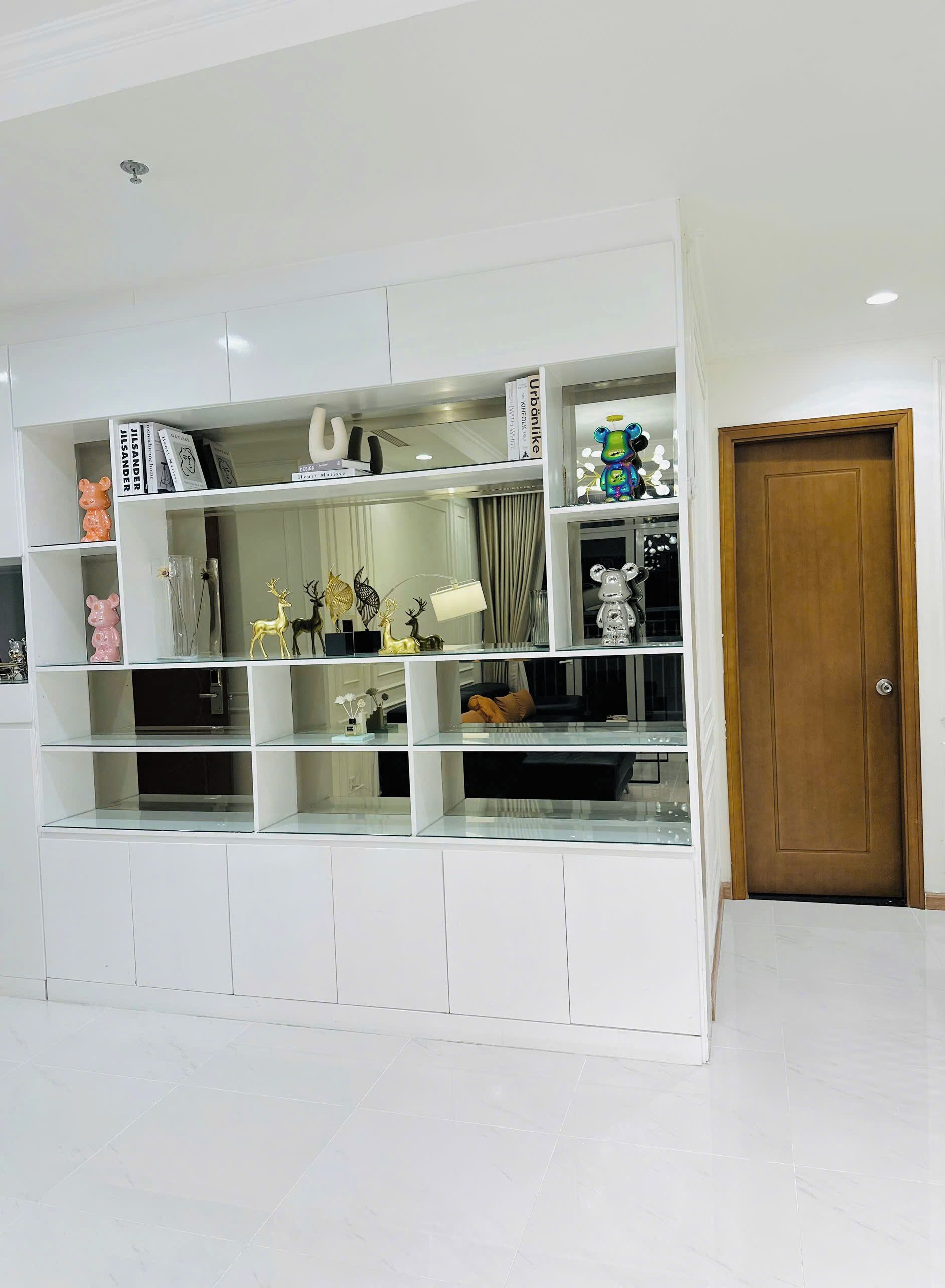 A white shelving unit with decorative items and a door to the right.