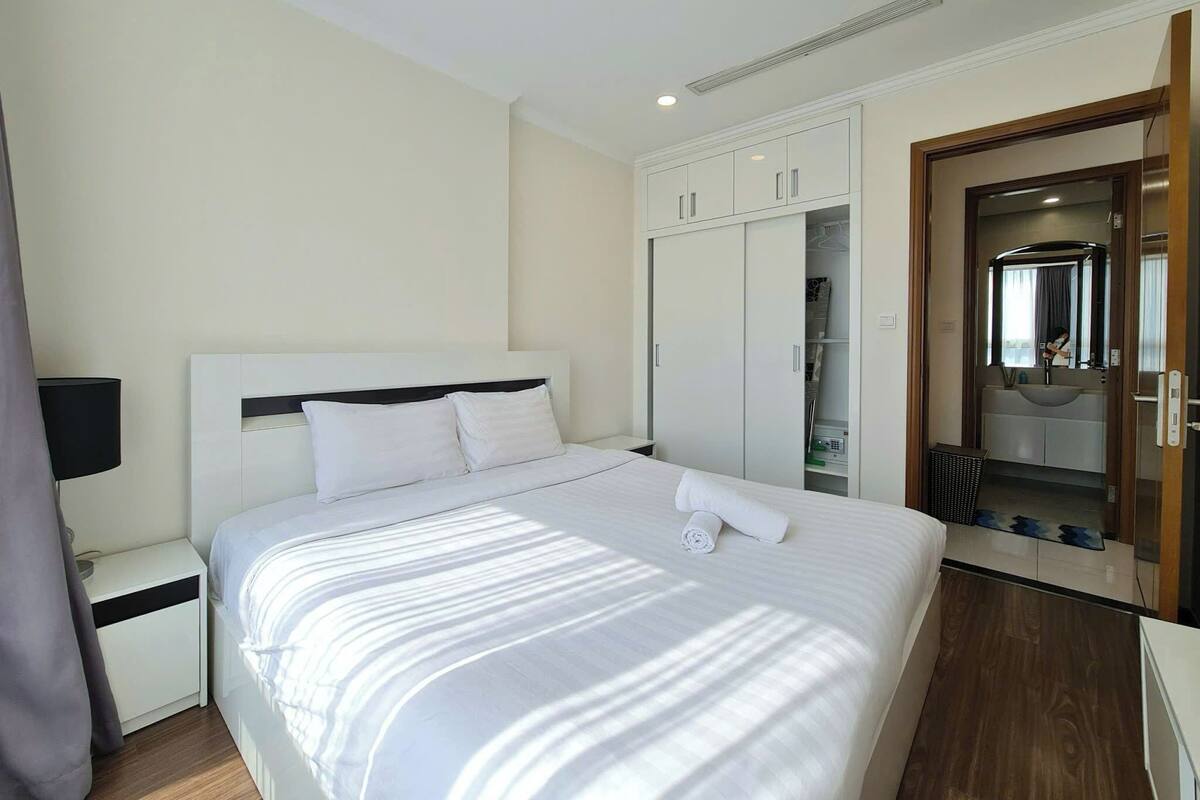 Una habitación de hotel con cama, armario, espejo y mesita de noche.