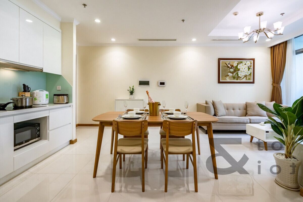 A modern living room with a dining area, a sofa, and a kitchen with white cabinets and a microwave.