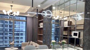 A modern dining area with a large table, chairs, and a view of the city through large windows. - Cozy- Vinhomes Central Park Apartments (Ho Chi Minh City)