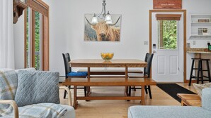 Comedor con mesa de madera, sillas, candelabro y un cuadro grande de un toro en la pared.